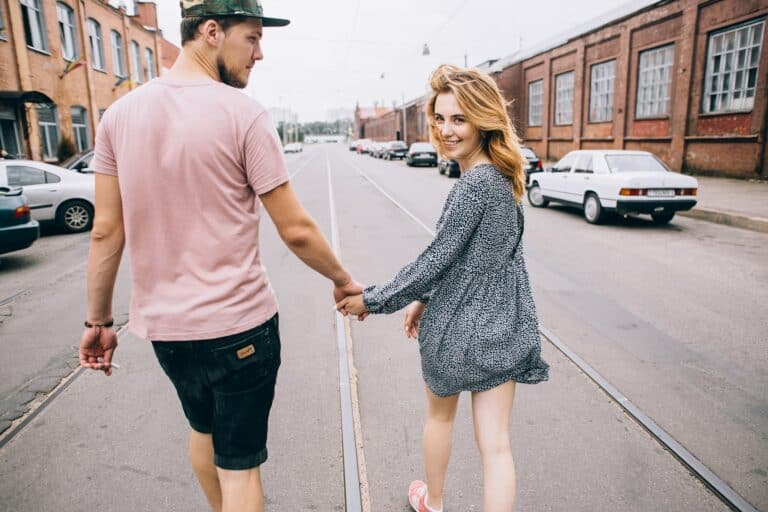 A happy couple are walking down a city street holding hands.